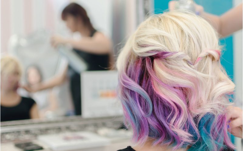 Vrouw in een salonstoel die Platinum Over the Rainbow underdye haar krijgt