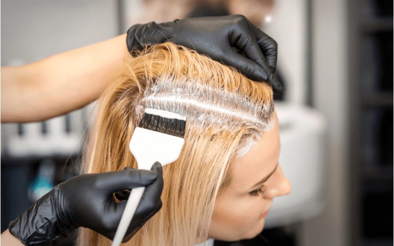 Vrouwen bleken haar haar thuis met handschoenen en een kleurborstel