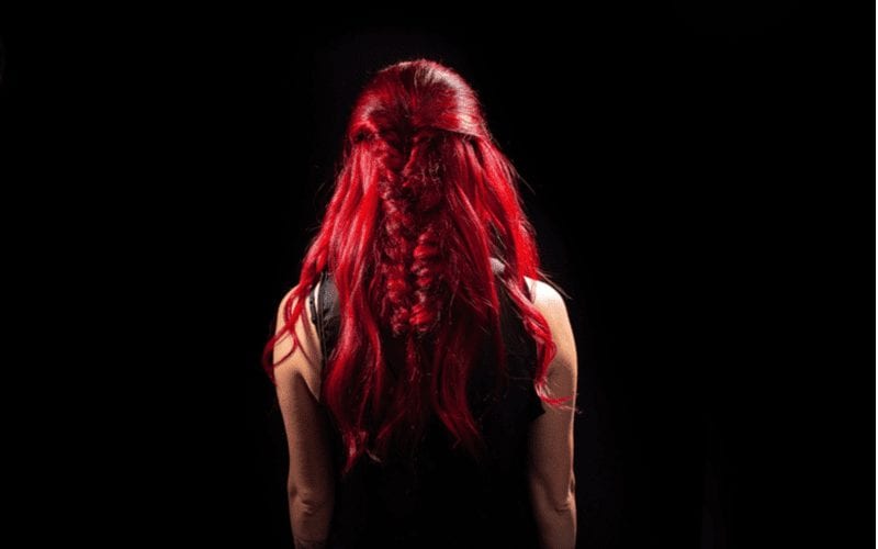 Vrouw met Ariel rood haar staat en kijkt naar een zwarte muur