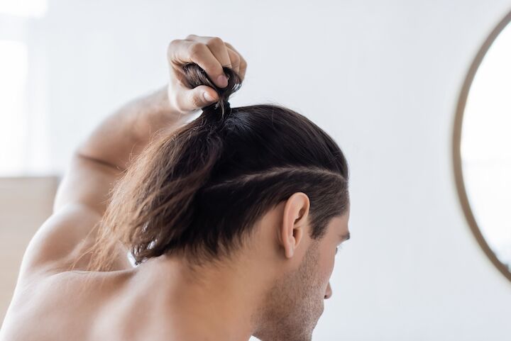 Man die een rommelig man Bun kapsel maakt