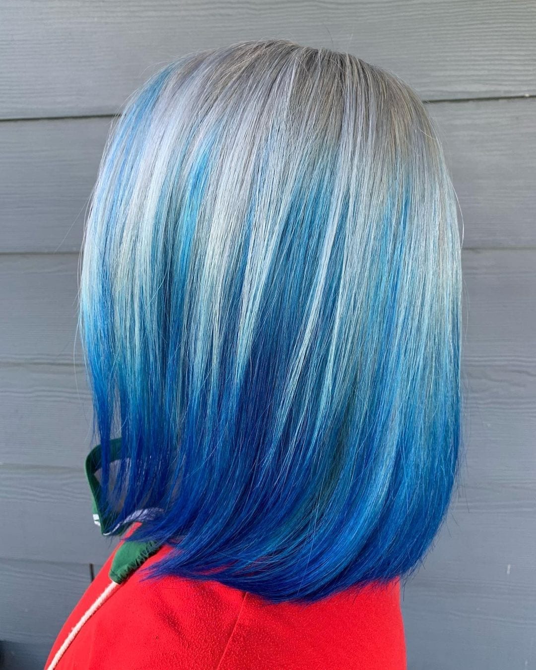 Persoon met lang haar dat blauw is en bij de wortels grijs wordt.