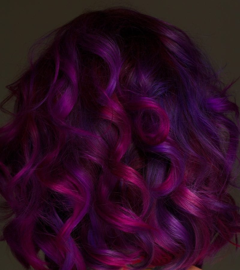 Mooi model met paars haar staat tegen een donkerbruine achtergrond