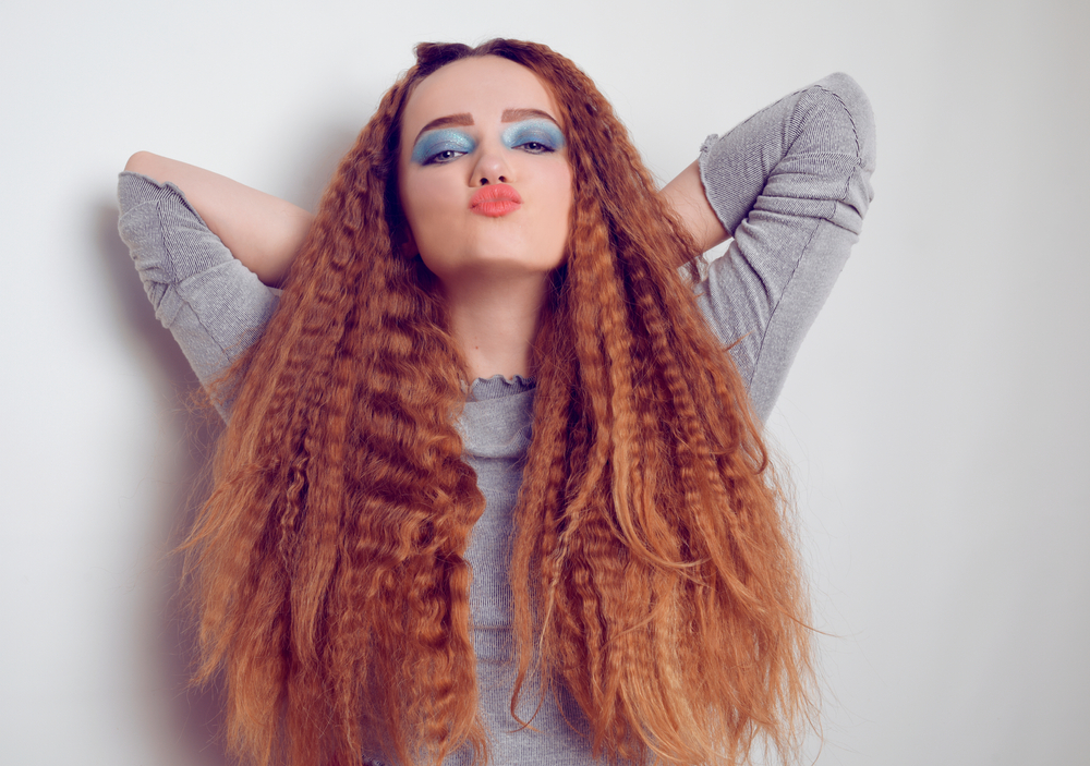 Gekrulde strengen op een vrouw die haar armen boven haar hoofd houdt