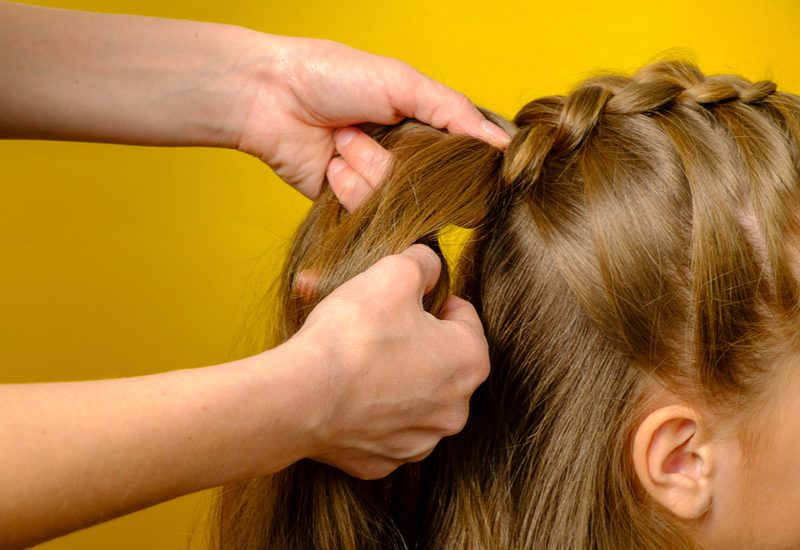 Vrouw doet een Franse vlecht, een van de beste beginnersvlechten voor kort haar, op een tiener