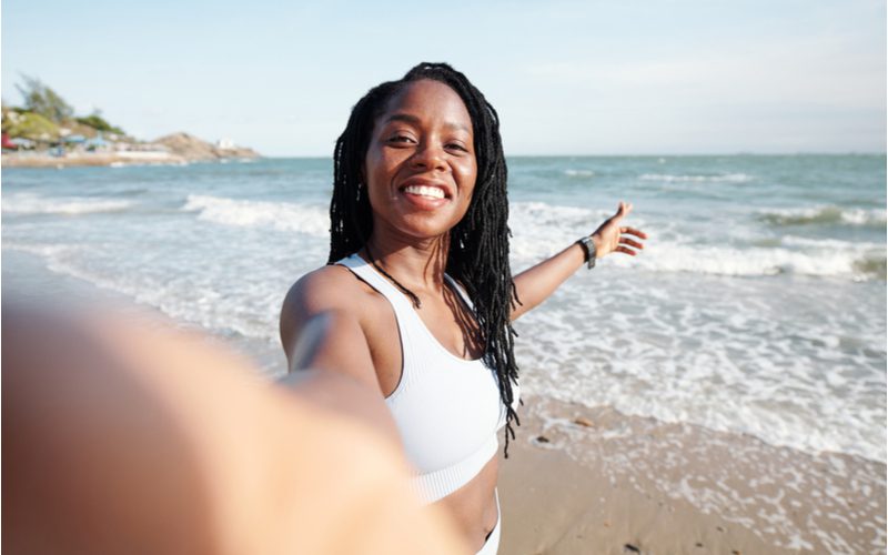 Losse Golvende Zusterlocks op een meisje in een wit zwempak op een strand