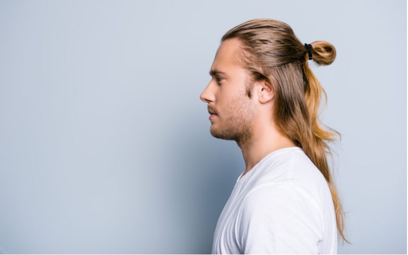 Half-Up Low Pull-Through Bun op een man in een wit overhemd in een blauwe kamer in een zijprofiel foto