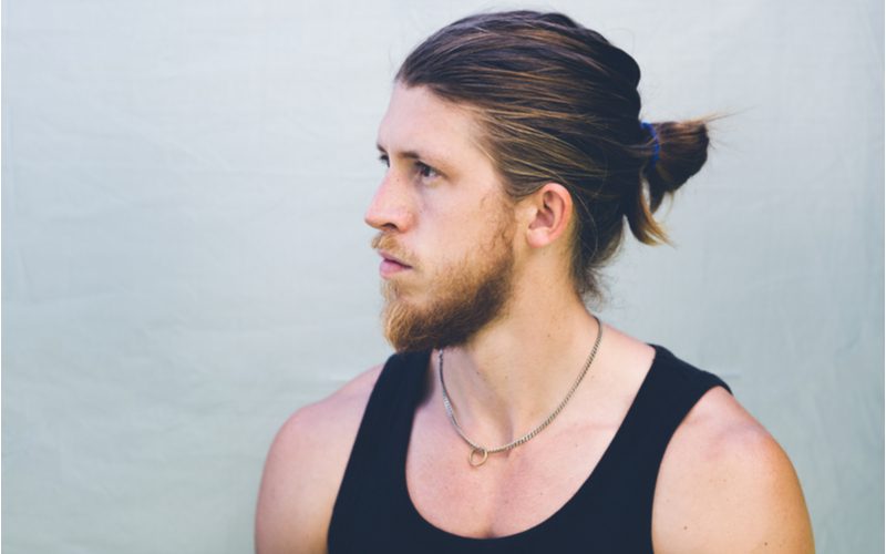 Last-Minute Vertical Loop Man Bun op een man in een zwarte tank top in een grijze kamer