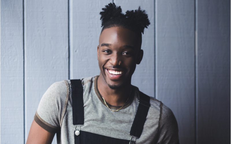 Double Puff Man Buns op een man in overalls en een grijs shirt