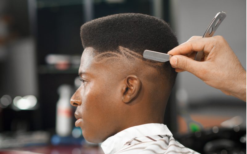 High Top Bald Fade op een zwarte man die een geschoren ontwerp krijgt in de achterkant van zijn haar