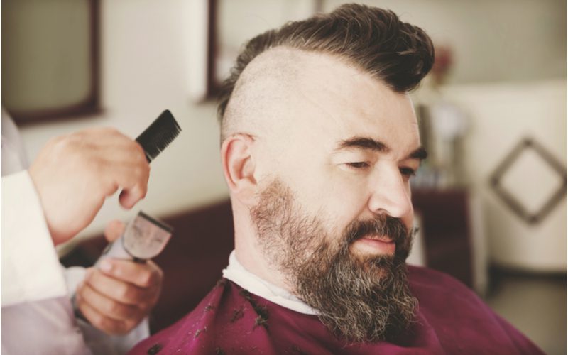 Wedge Mohawk kapsel voor terugwijkende haarlijnen geknipt op een man in een kappersstoel