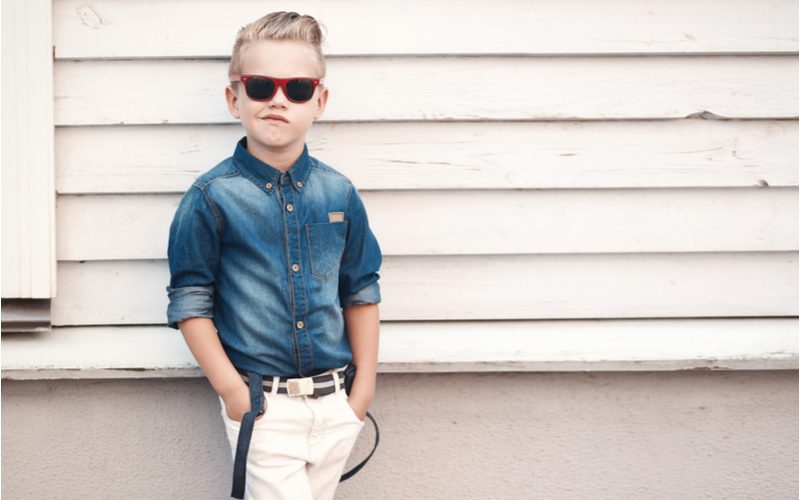 Greaser Pompadour Fade (een populair jongenskapsel) gedragen door een jongetje in een spijkerjasje met zijn handen in zijn zakken.