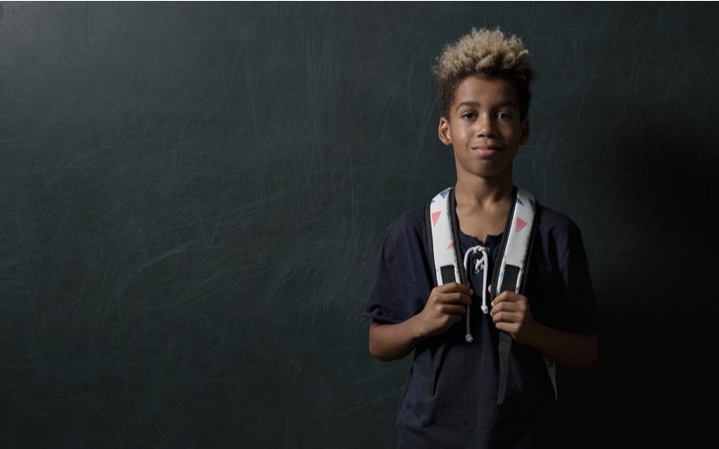 High-Top Taper With Frosted Tips jongenskapsel op een Afro-Amerikaanse jongen in een rugzak