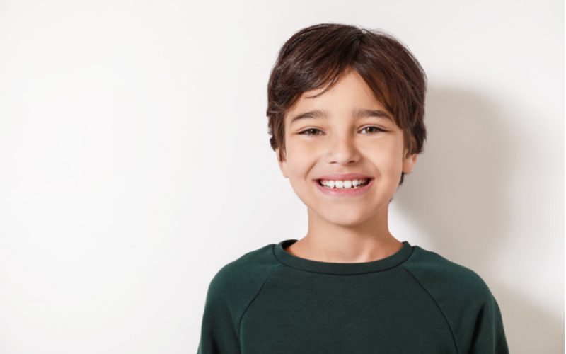 Taps toelopende snit met gespleten pony's op een kleine jongen met een zijscheiding en een grote glimlach in een sweatshirt met ronde hals.