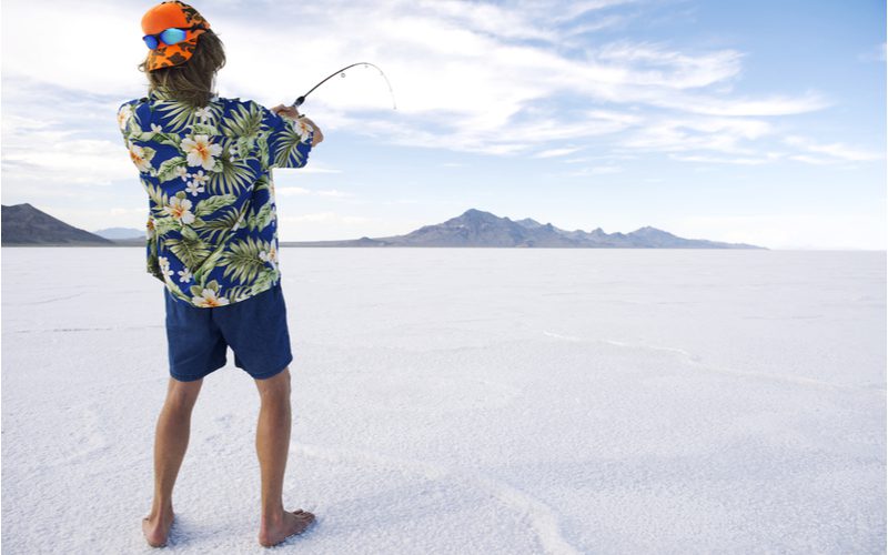 Redneck met een moderne mul vissend vanuit een opgedroogd meer naast een aantal kleine bergketens