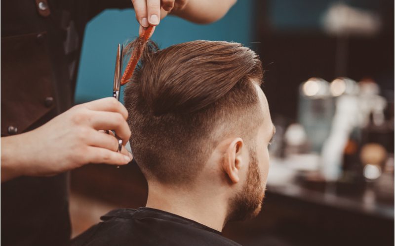 Voor een stuk over populaire kapsels voor mannen, een man met een lange, gladde pompadour die zijn bovenhaar laat knippen...