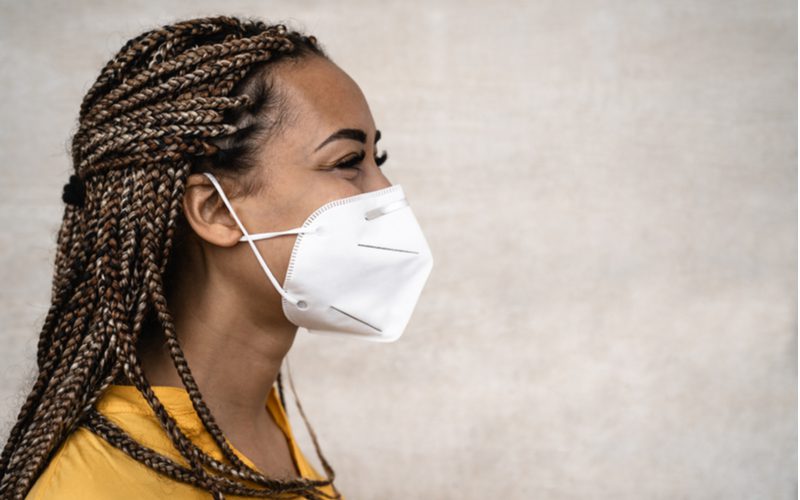 Box Braids Half-Updo op een zwarte vrouw in een gele trui in een zij-profiel foto.