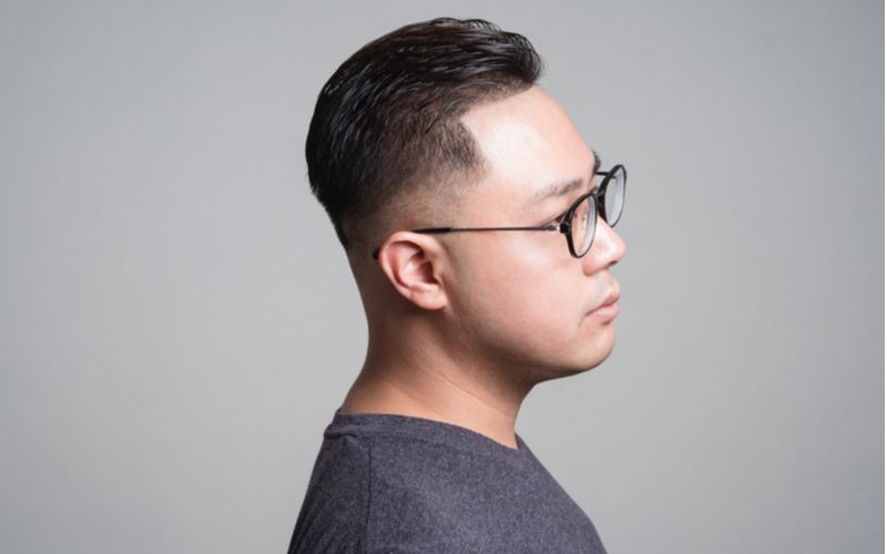 zijprofiel van een man met een Pompadour Low Skin Fade kapsel die een bril draagt in een studio