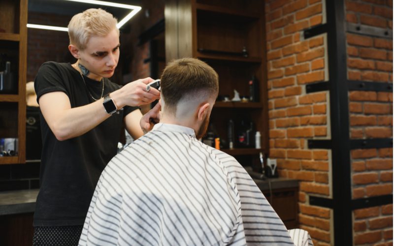 Mohawk Bald Drop Fade wordt geknipt door een kapper met gebleekt blond haar