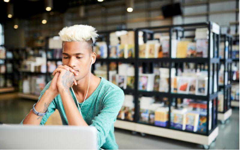 Gebleekte Mohawk Burst Fade op een man in een groen shirt in een boekwinkel.