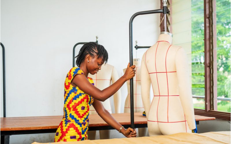 Zwarte vrouw met tribale vlechten die als mini dreads naar de zijkant zijn getrokken duwt een mannequin