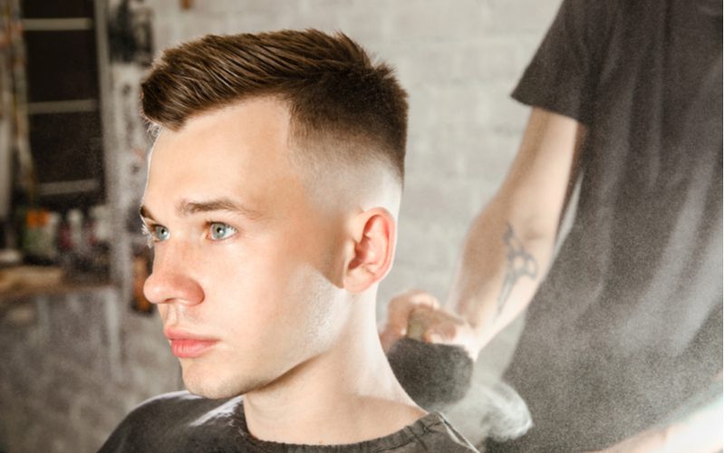 Man met een spiked kapsel met veel drop fade zit in een kappersstoel