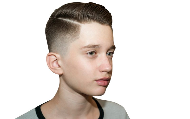 Knappe jonge Europese jongen met een geschoren side-part low fade kapsel.