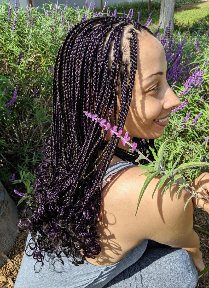 Zwarte vrouw die Skinny Box Braids draagt met krullende uiteinden