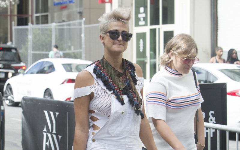 Vrouw met een punk rock faux hawk kapsel in een witte overall en een witte BH wandelend op straat in NYC.