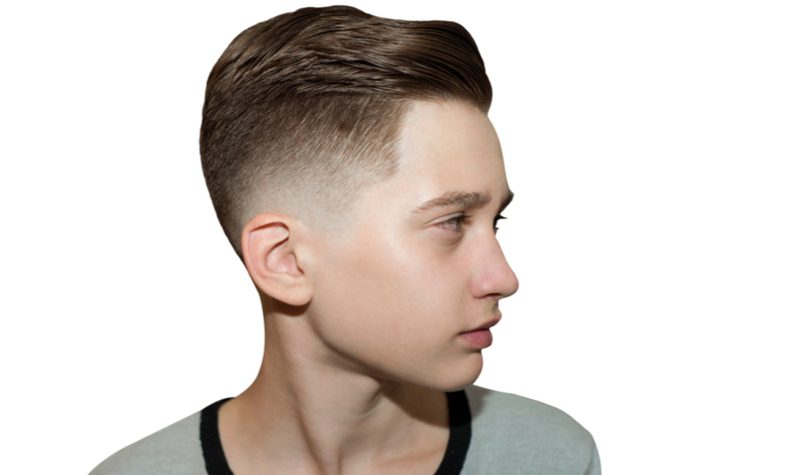 Mid Drop Bald Fade kapsel op een man in een ringer shirt in een witte studio.