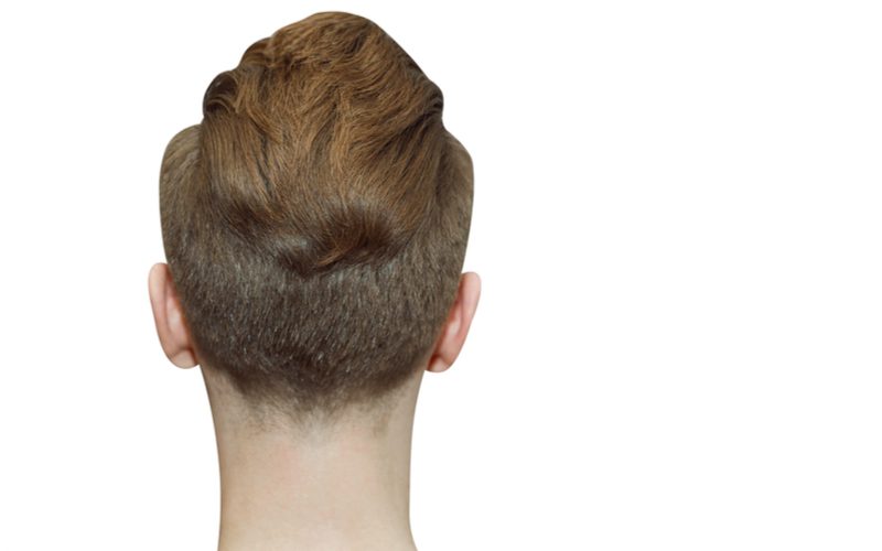 Pompadour Faux Hawk op een man met het gezicht naar een witte muur en wegkijkend van de lezer