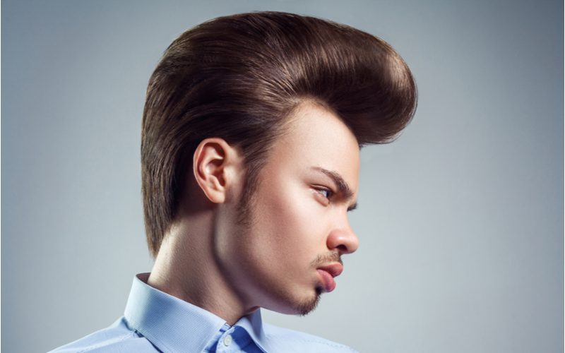 Perfect gecoiffeerde Pompadour op een man in een blauw overhemd met knoopjes.