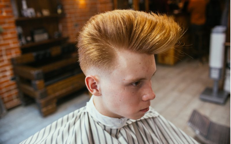 Psychobilly Wedge pompadour kapsel op een man met rood haar in een gestreepte cape