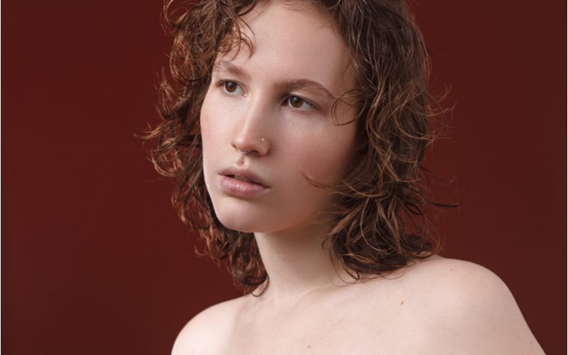 Wet-Cut Curly Lob op een vrouw in een bordeauxrode kamer