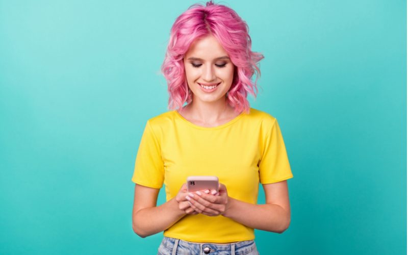 Curly 70s-Inspired Bob gedragen door een vrouw in een geel shirt en lichtgewassen jeans