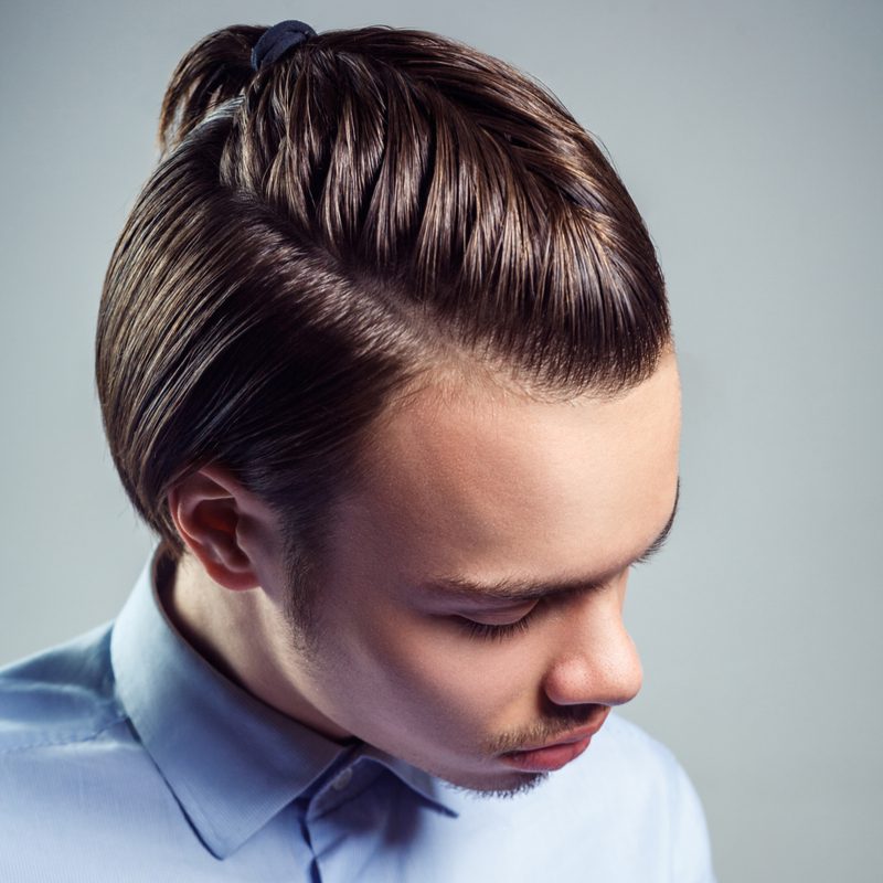 Hipster latino man die franse vlechten draagt voor mannen en ook een volledig dichtgeknoopt blauw hemd draagt