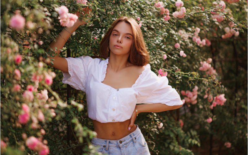 Long Curtain Bangs op een vrouw in een witte crop-top voor een stuk op bob met pony's