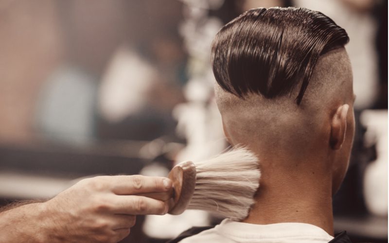 Man in een kappersstoel schommelend met een undercut undercut kapsel.