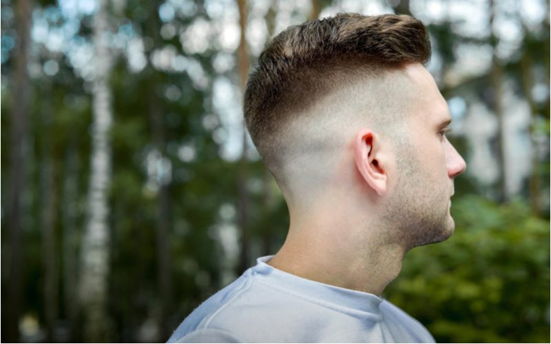 Jonge man met een undercut skin fade draagt een tie die dye overhemd en kijkt links naar het bos van zijn schouder.