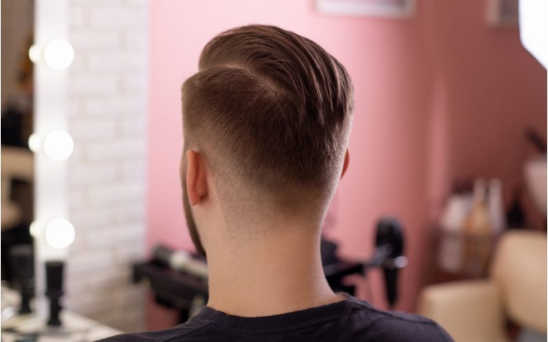 Man met een undercut zijdeel kijkt zittend naar de spiegel in een kapperszaak