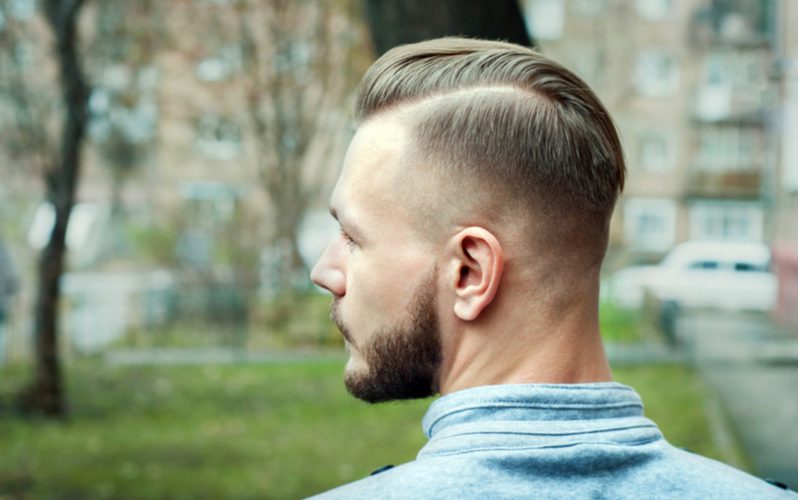 Gent met een sportieve undercut fade kijkt naar rechts en draagt een grijs sweatshirt met kraag.