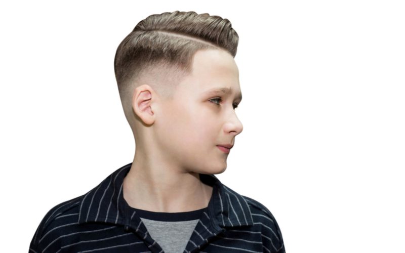 Jongen in een zwart shirt pronkt met zijn gekamde undercut fade kapsel in een studio.