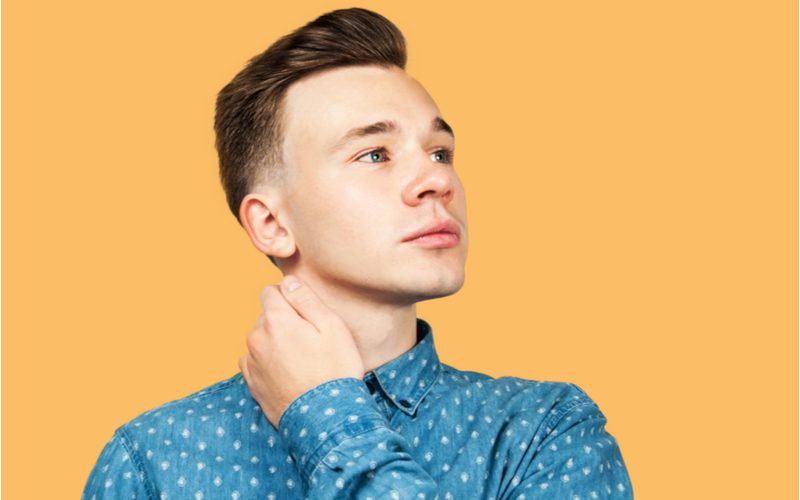 Jonge man met een pompadour undercut fade kapsel in een blauw shirt in een oranje kamer.