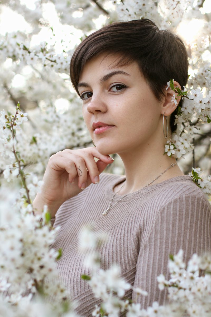 Pixie bob kapsel op een vrouw die in een wit bloemenveld staat
