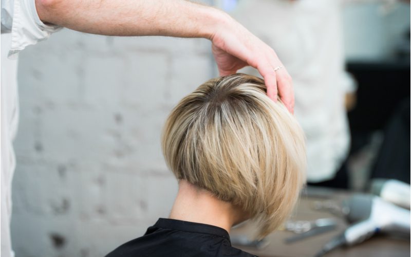 Vrouw met een Inverted Bob With Shadow Root krijgt haar hoofd vastgehouden door een hand