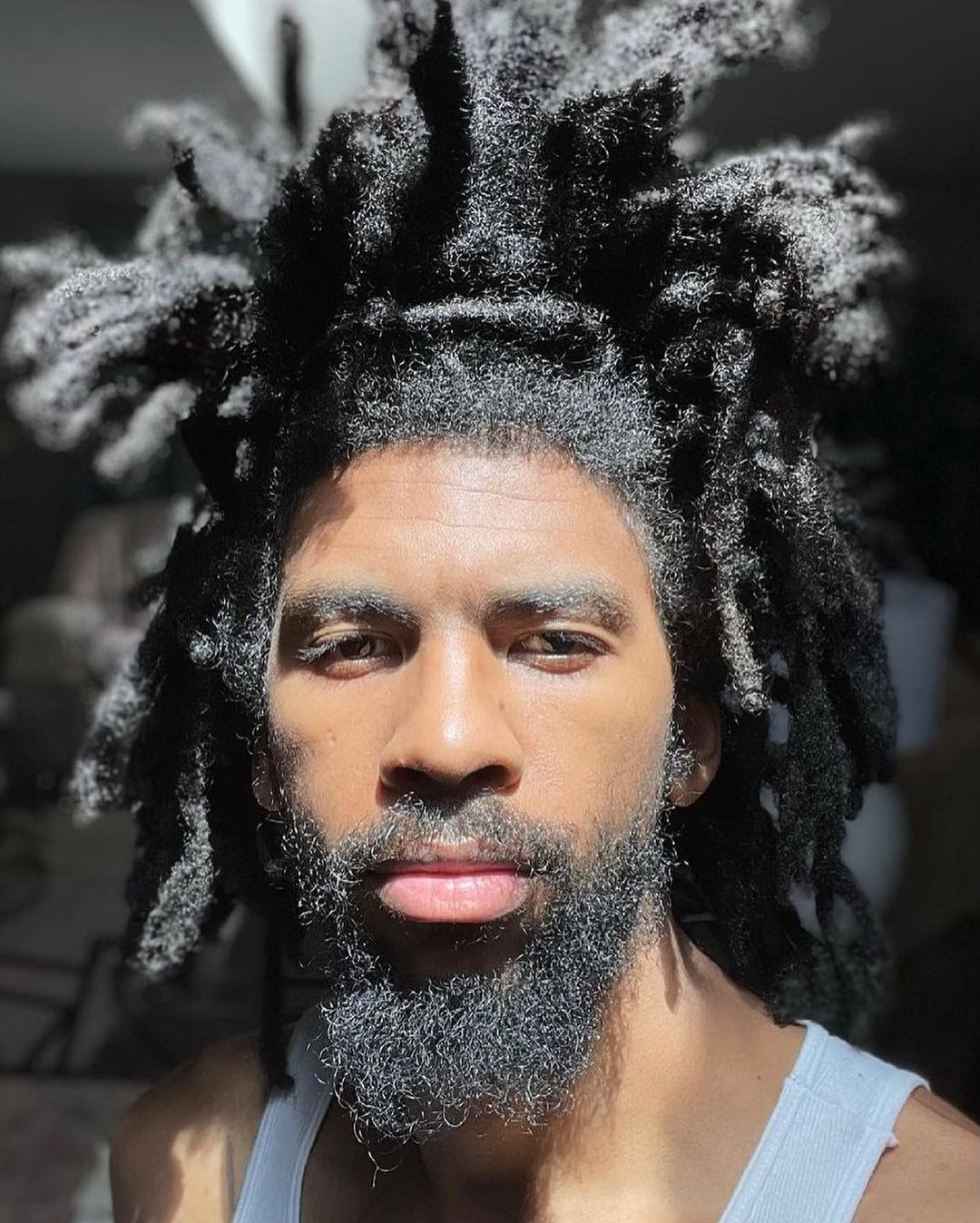 Man met fuzzy freeform locs in een witte tank top en laat zijn dikke haar echt stromen