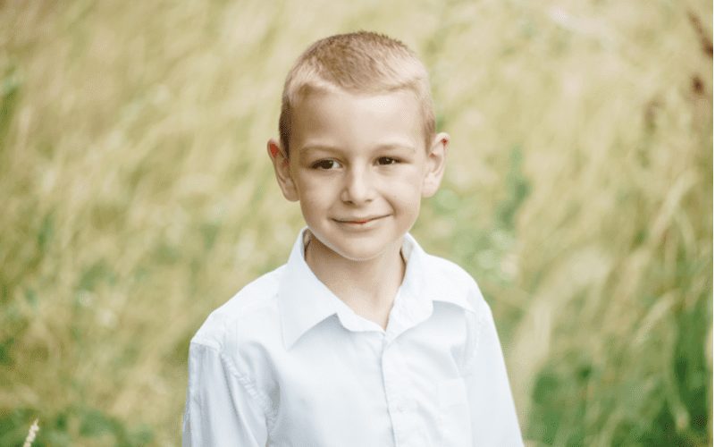 Buzz Cut Fade op een kind in een wit shirt in een maïsveld.