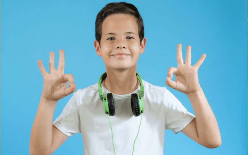 Foto van een jongen met een Over and Back Tapered Cut die twee ok-tekens geeft met zijn handen