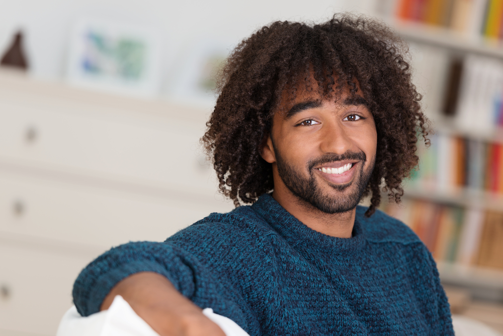 Natural Spiral Perm afgebeeld op een man in een blauw shirt lachend met een afro