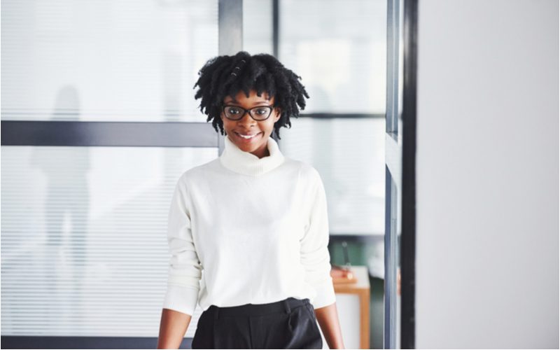 Accessorized Locs gedragen door een zakenvrouw in een witte blouse en zwarte rok in een modern kantoor.