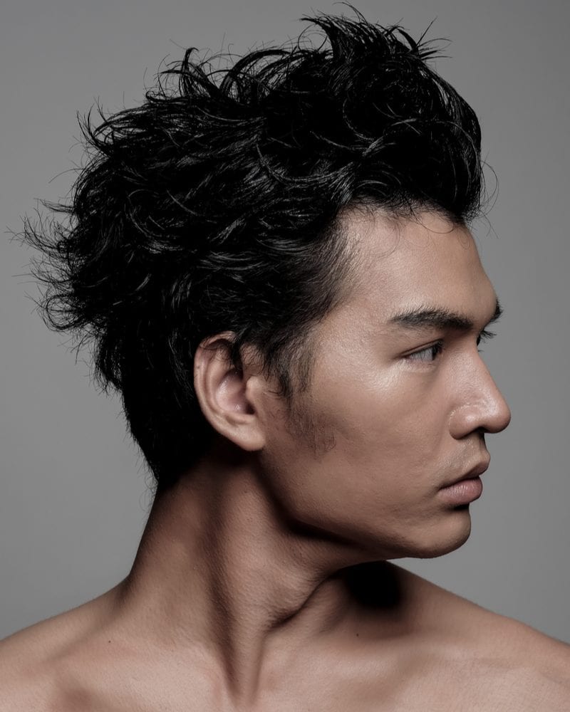 Jonge aziatische man zonder shirt draagt een populair aziatisch mannenkapsel van een piekerige lange updo